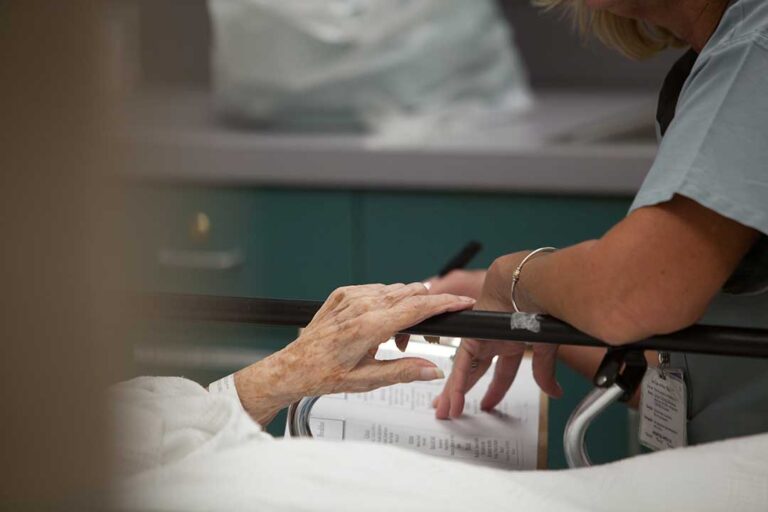 Older adult and family member reviewing care notes together at a kitchen table.